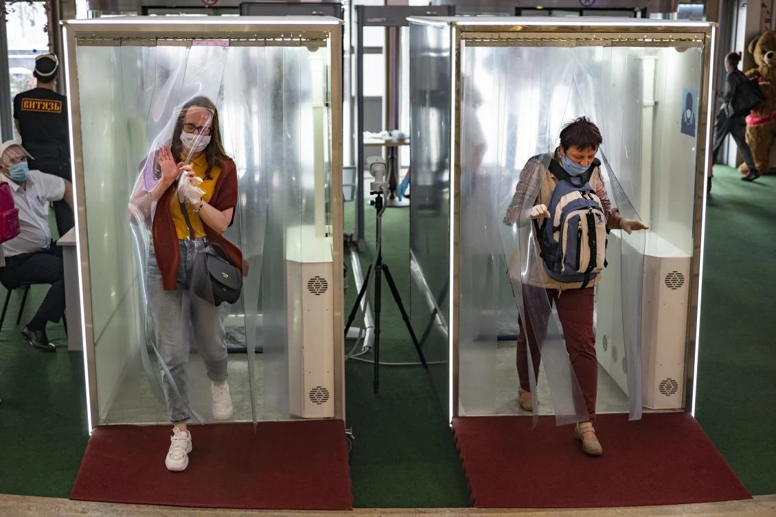 People wearing face masks and gloves pass through disinfecting cabins entering a shopping mall in Moscow, Russia, Monday, Aug. 3, 2020. Moscow authorities require residents to wear mask on public transport, in stores and other confined public spaces. (AP)