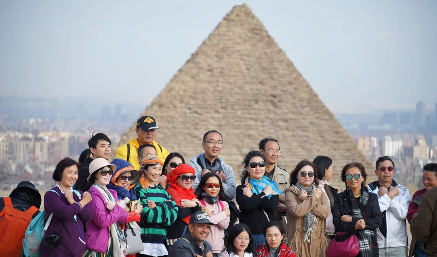 Tourists pose for a group picture at the Giza pyramids necropolis on the southwestern outskirts of the Egyptian capital Cairo on December 29, 2018, with the pyramid of Menkaure (or Menkheres) seen in the background. (AFP)