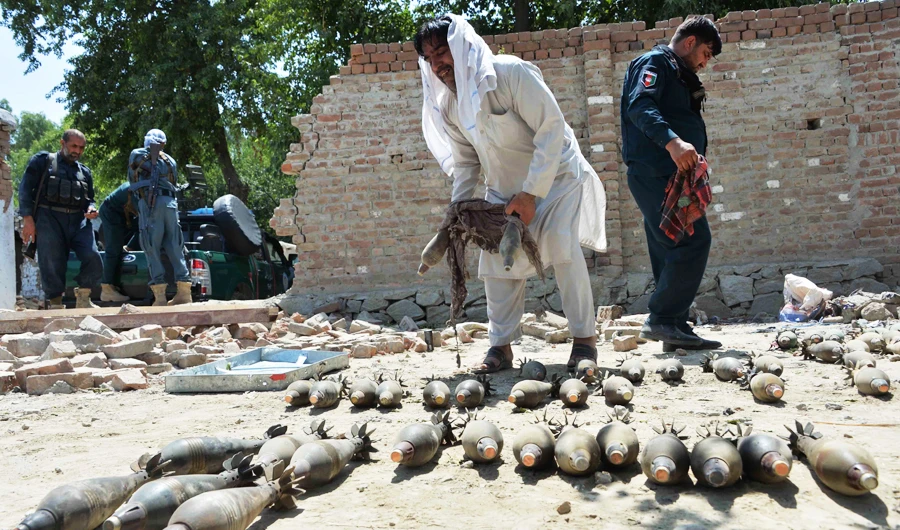 Afghan security officials inspect seized weapons near a damaged residential house from where a group of Daesh gunmen were firing mortar shells. (AFP)