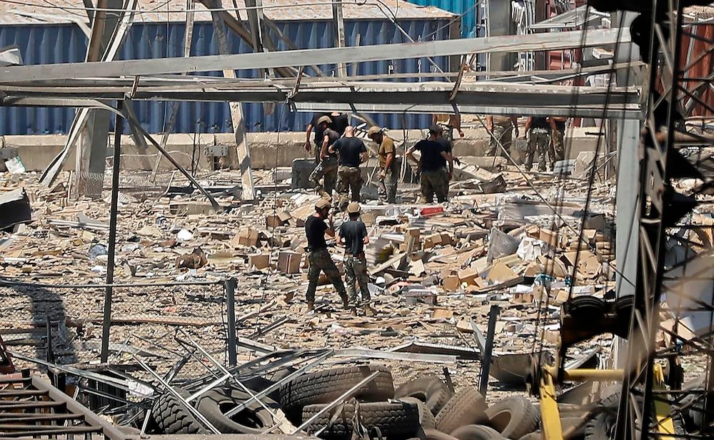Rescuers and civil defense search through the debris at Beirut port’s silo on Aug. 5, 2020 in the aftermath of a massive explosion in the Lebanese capital. (AFP)