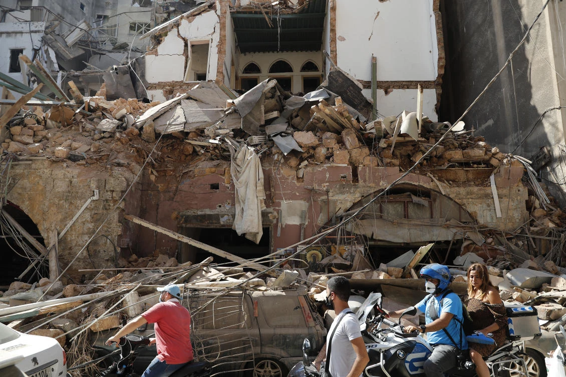 Citizens ride their scooters and motorcycles pass in front of a house that was destroyed in Tuesday's massive explosion in the seaport of Beirut, Lebanon, Wednesday, Aug. 5, 2020. (AP)