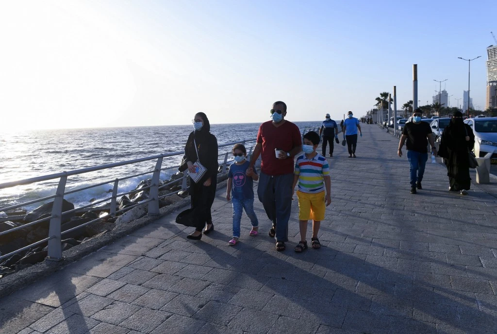People stroll down the seafront promenade in the Saudi seaport of Jeddah, on June 21, 2020, as the country re-opens following the lifting of a lockdown due to the COVID-19 pandemic. (AFP)