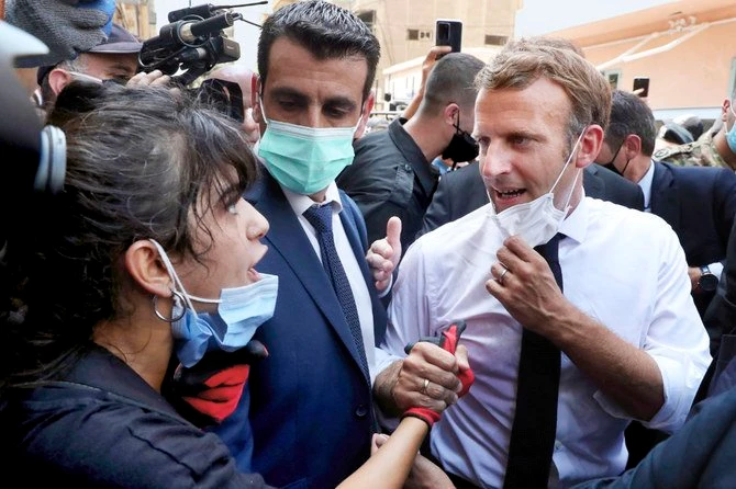 French President Emmanuel Macron speaks to the woman who asked him for help during his visit to Beirut’s devastated Gemmayzeh neighborhood. (AP)