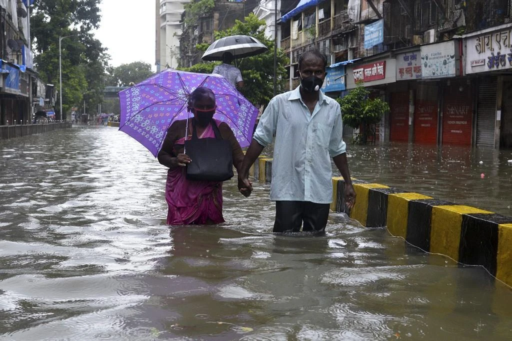 Senior citizens wade in knee deep water along a flooded road during a heavy monsoon rainfall in Mumbai on August 4, 2020. (File/AFP)