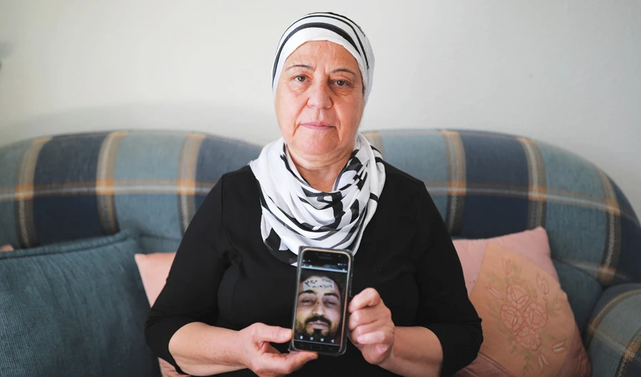 Mariam Hallak from Syria holds a phone with a picture of her dead son Ayham, who she says was identified among thousands of images showing bodies of dead detainees in Syrian regime detention facilities. (Reuters)