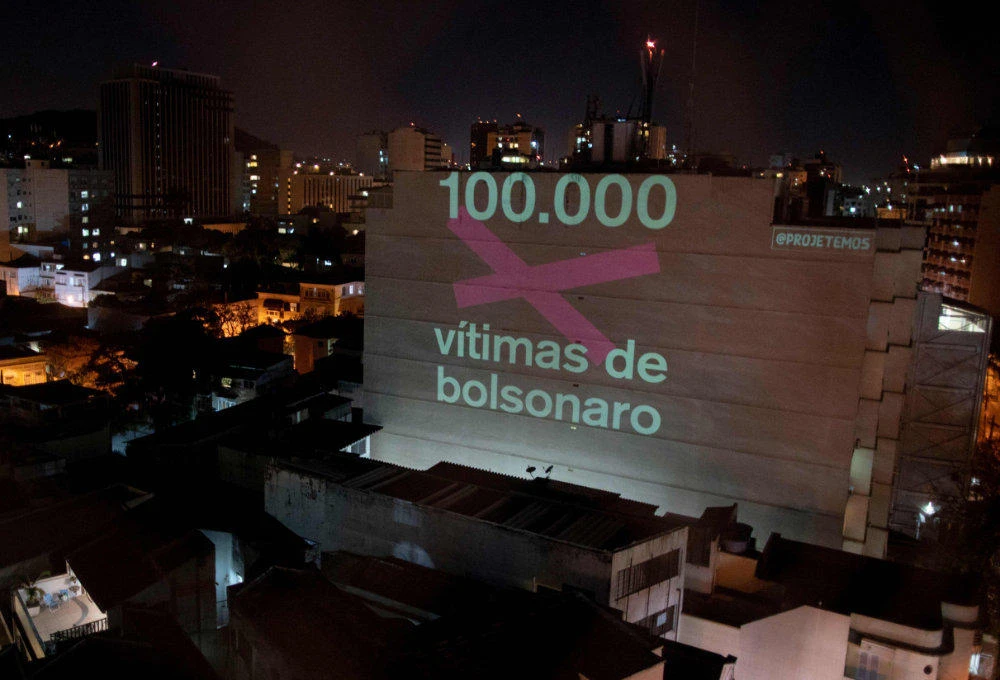 A projection on a building honoring the 100,000 victims who died of the novel coronavirus COVID-19 in Brazil reads "100,000 Victims of (Brazilian President Jair) Bolsonaro" in Botafogo neighborhood in Rio de Janeiro, Brazil, on August 8, 2020. (AFP / Mauro Pimentel)