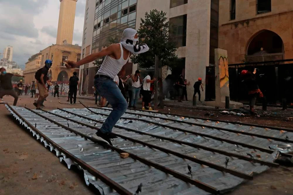 Lebanese protesters, enraged by a deadly explosion blamed on government negligence, clash with security forces near an access street to the parliament in central Beirut Sunday, (AFP)