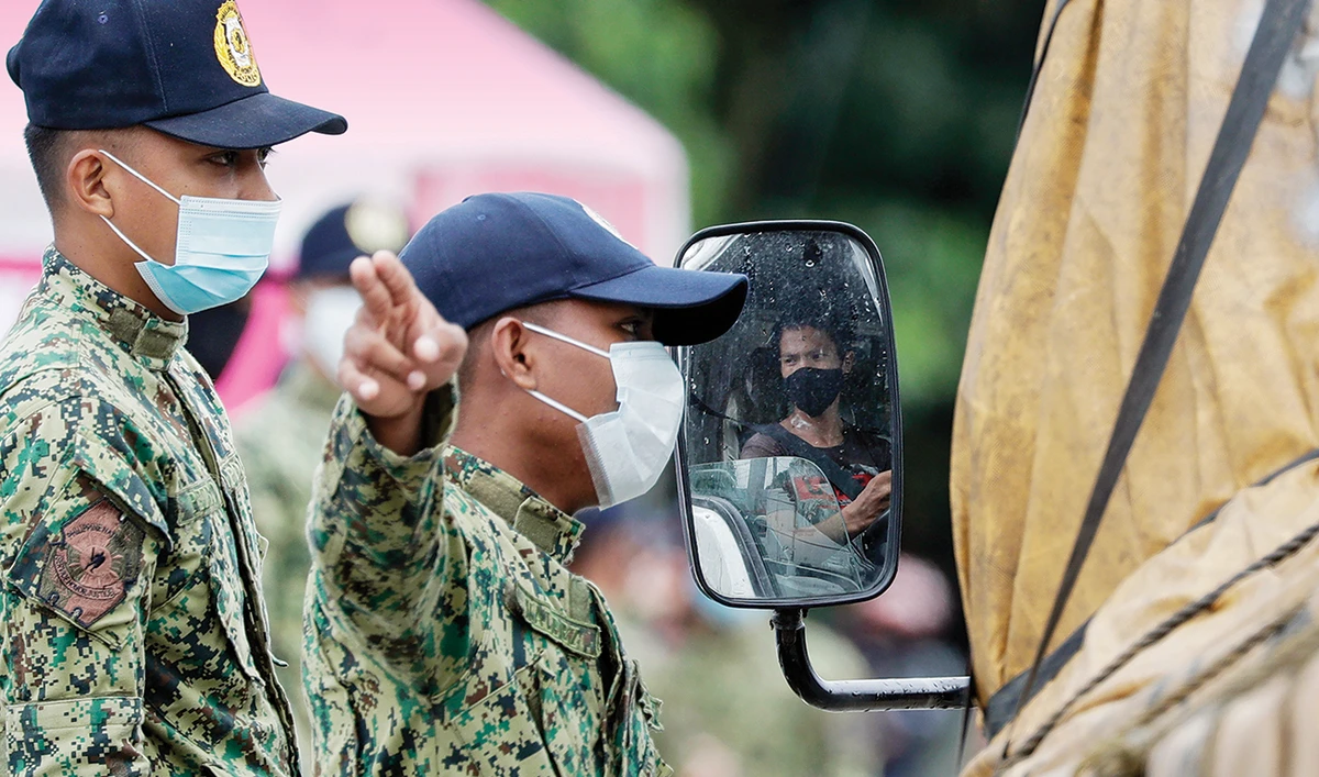 Police officers instruct a driver as they implement stricter quarantine measures to curb the spread of COVID-19 at the border of Bulacan province and Caloocan city. (AP)