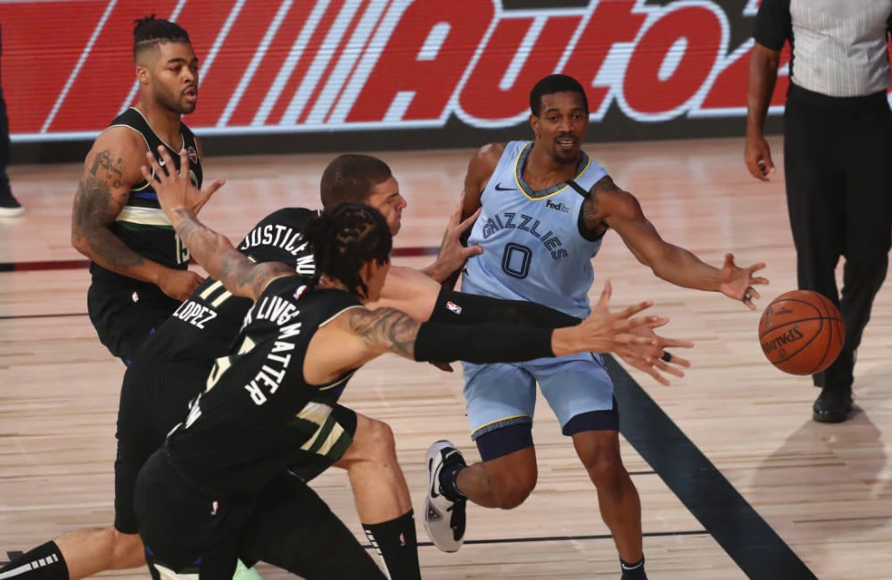 Memphis Grizzlies guard De'Anthony Melton passes against Milwaukee Bucks center Brook Lopez (11) and forward D.J. Wilson (5) during an NBA basketball game on Aug. 13, 2020, in Lake Buena Vista, Florida. (Kim Klement/Pool Photo via AP)
