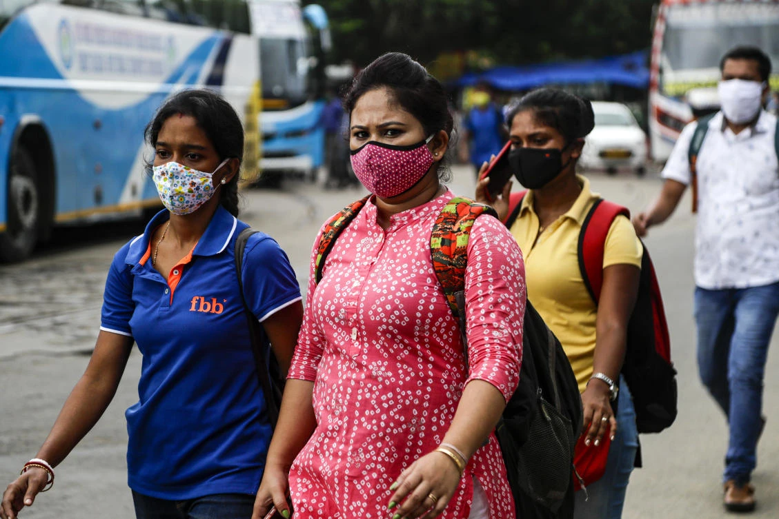 People wearing face masks walk to catch buses in Kolkata, India, Friday, Aug. 14, 2020. (AP)