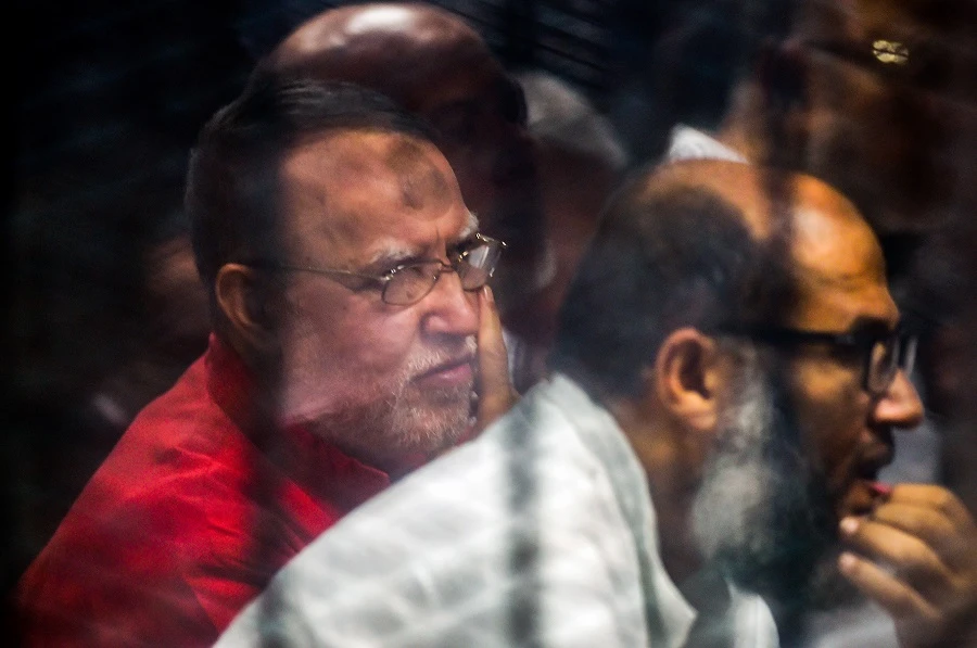 In this file photo taken on December 2, 2018 Senior Muslim Brotherhood member Essam al-Erian (L) sits behind bars in a glass cage during his trial at a make-shift courthouse in southern Cairo. (File/AFP)
