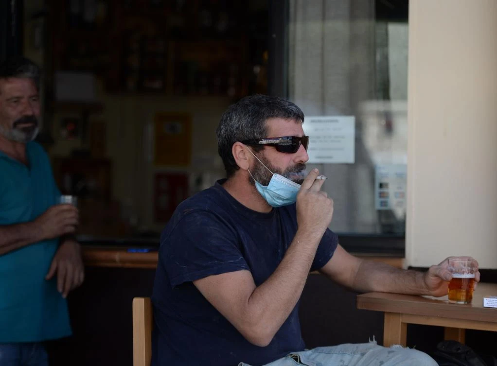 A man smokes while drinking beer at the terrace of a bar in Sevilla on August 13, 2020. Spanish regions Galicia and Canary Islands attracting tourists introduced outdoor smoking bans to curb the coronavirus as a top domestic medical body called for a more coordinated response and tougher punishment for rule breakers. (AFP)