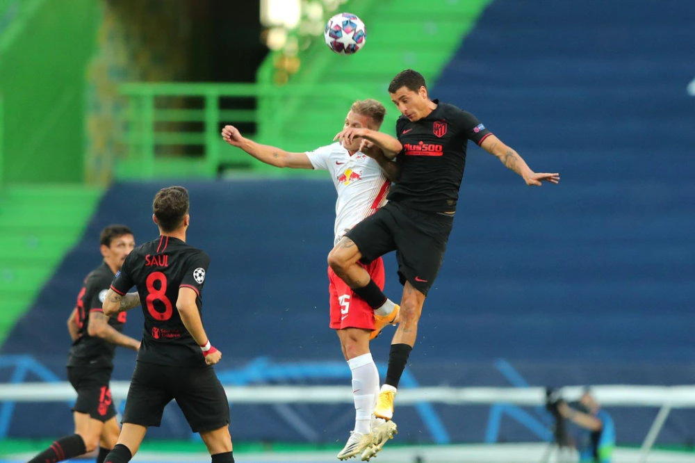 Leipzig's Spanish midfielder Dani Olmo (L) jumps for the ball with Atletico Madrid's Uruguayan defender Jose Gimenez during the UEFA Champions League quarter-final football match between Leipzig and Atletico Madrid at the Jose Alvalade stadium in Lisbon on August 13, 2020. (AFP / POOL / Miguel A. Lopes)