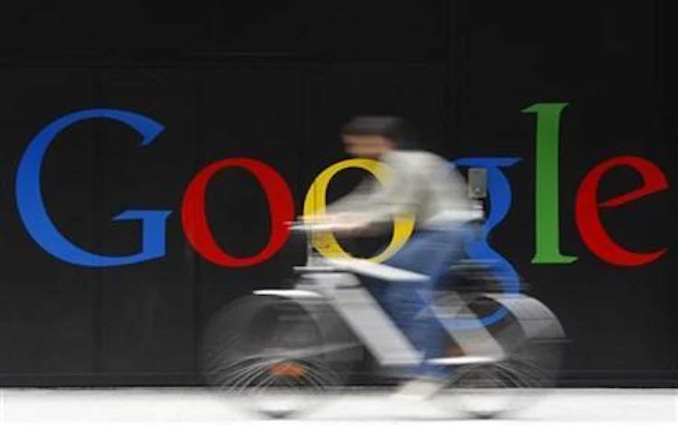 An employee rides her bike past a logo next to the main entrance of the Google building in Zurich. (Reuters)