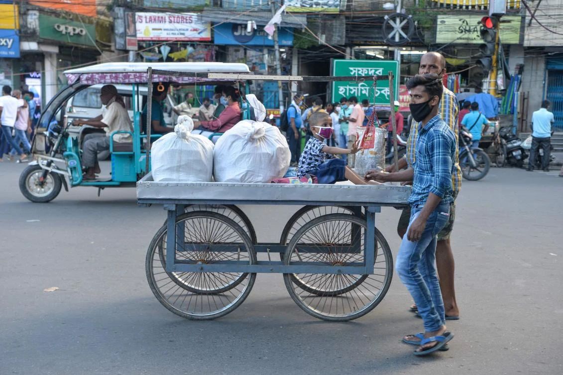 A man and his son push a cart where a young boy sits in Siliguri on August 19, 2020, as a state-imposed lockdown will be held on August 20 and 21 against the surge in COVID-19 coronavirus cases. (AFP)