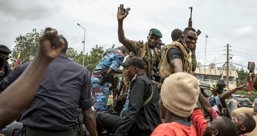 People cheer in celebration as security forces drive through the streets of the capital Bamako, Mali, Wednesday, Aug. 19, 2020, a day after armed soldiers fired into the air outside President Ibrahim Boubacar Keita's home and took him into their custody. (AP)