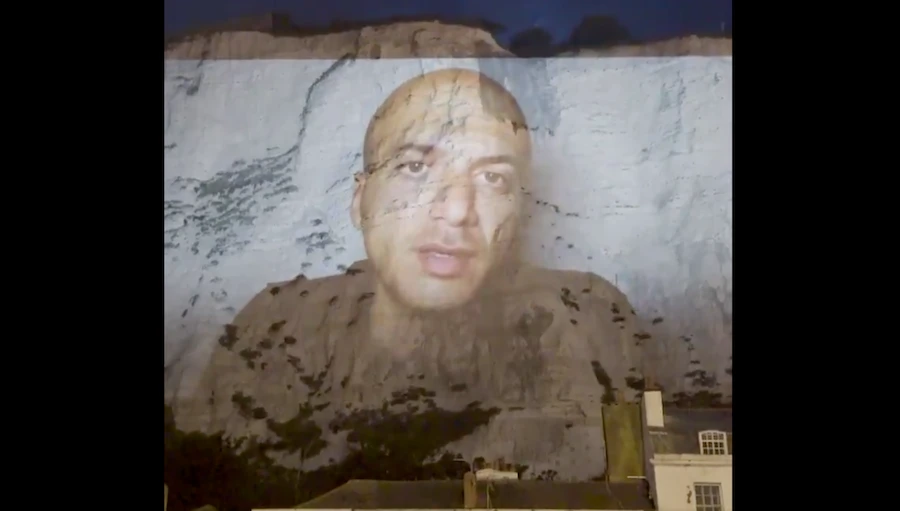 Syrian refugee filmmaker Hassan Akkad recalled his “terrifying” journey across the English Channel and into the UK in a video projected on the White Cliffs of Dover on Friday, in an effort to raise compassionate awareness for migrants being smuggled into the country. (Screenshot)