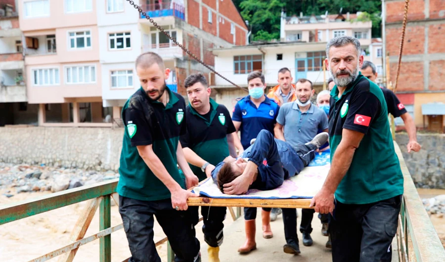 People carry a rescued person from the scene after floods caused by heavy rain in the mountain town of Dereli in Giresun province, along Turkey's Black Sea coastline, Sunday, Aug. 23, 2020. (AP)