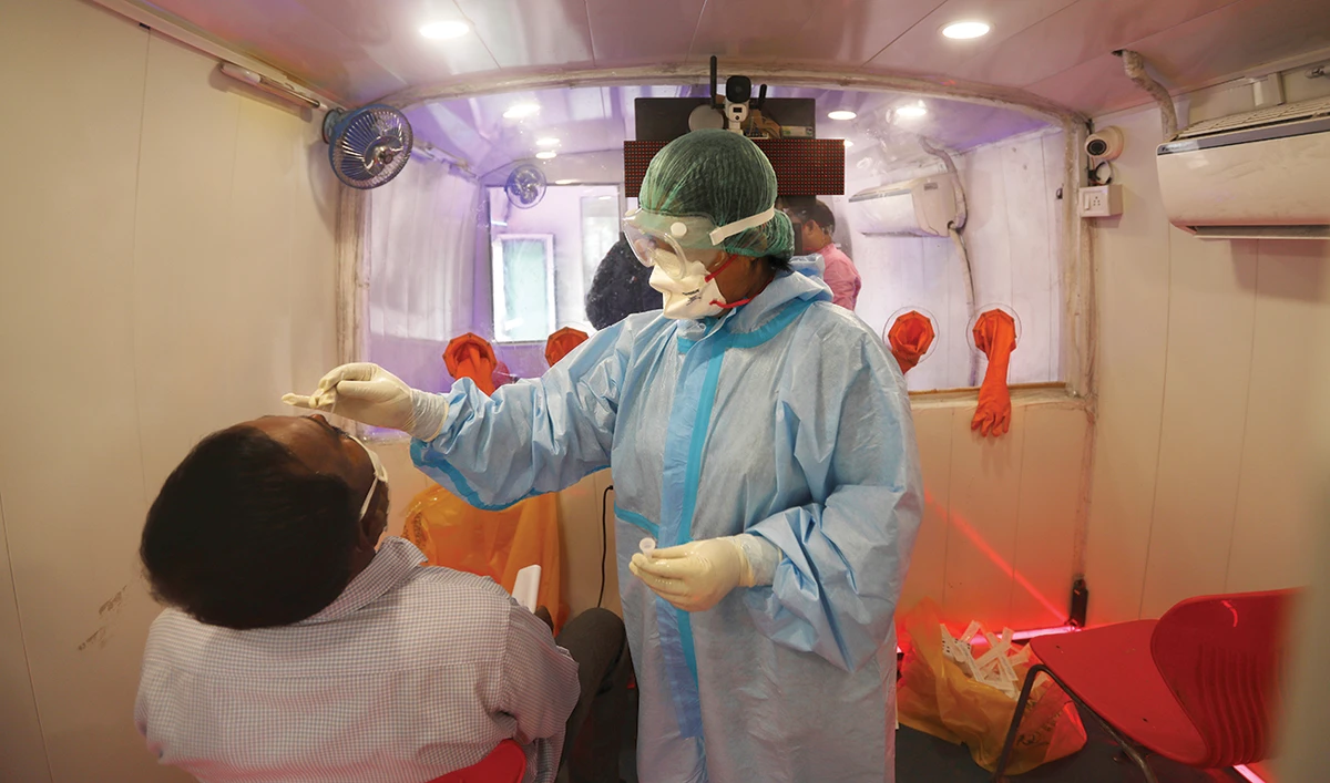 A health worker inside a mobile lab takes a nasal swab sample for a COVID-19 antigen test in New Delhi, India. Some countries have already made a pre-departure COVID-19 test a mandatory requirement, while many others are seriously considering implementing the same for all incoming travelers. (AP)