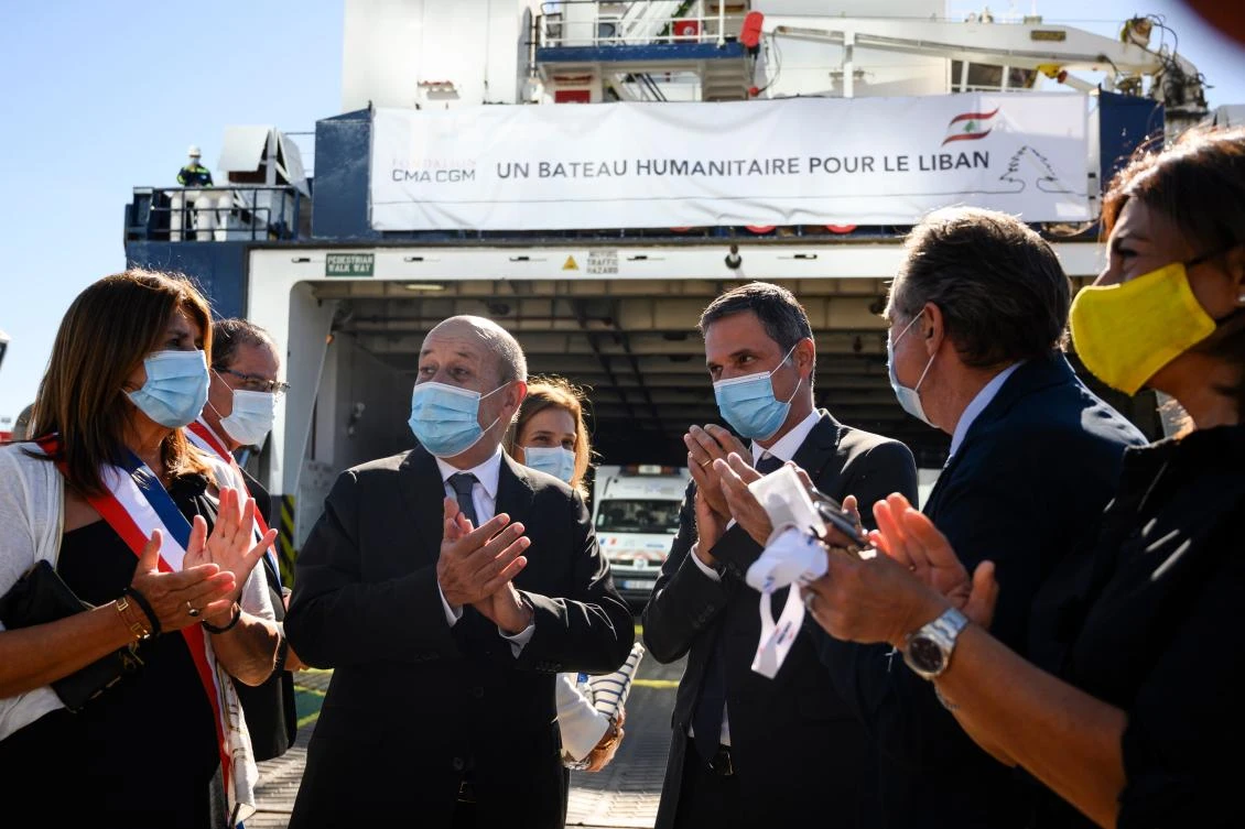 French FM Jean-Yves Le Drian, 2nd left, and Michelle Rubirola, Mayor of Marseille, left, applaud as a CMA-CGM container ship is loaded with humanitarian aid bound for Lebanon, Marseille, Aug. 25, 2020. (AFP)