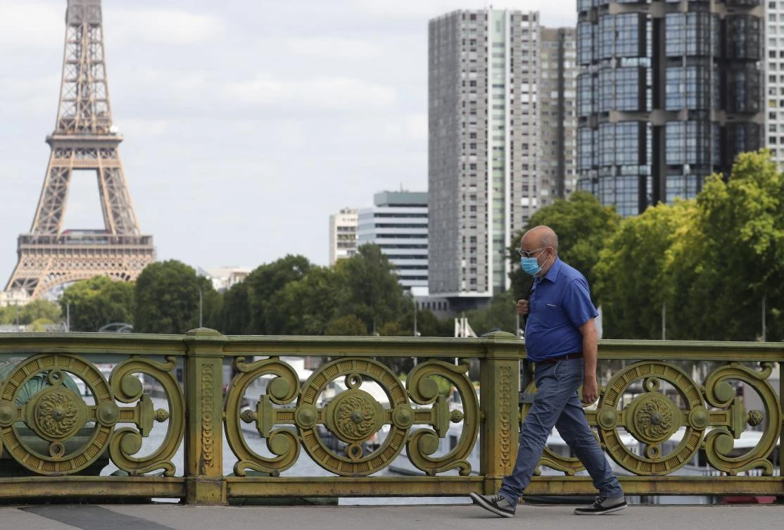 A man wears a protective face mask while walking across Pont Mirabeau bridge, near the Eiffel Tower, on August 27, 2020, in Paris. France's prime minister on August 27 announced face masks will become compulsory throughout Paris. (AFP)