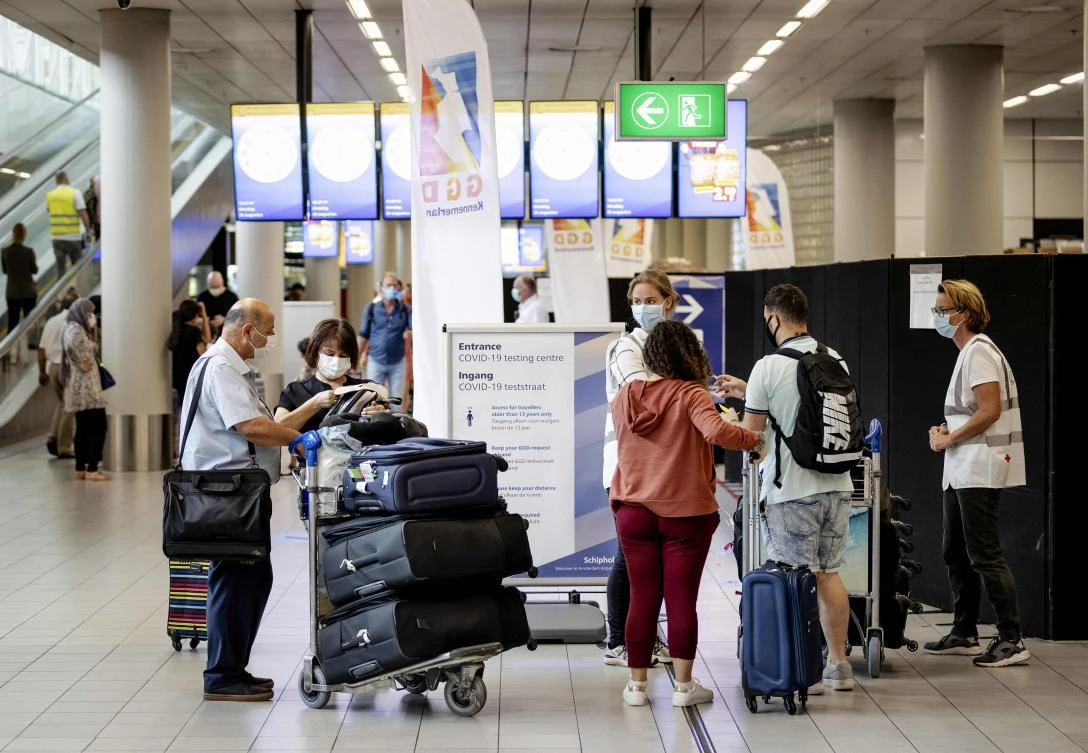 Passengers queue to be screened for Covid-19 at a testing station set up at Schiphol airport, near Amsterdam, on August 25, 2020. Travelers coming back from an orange or a red area can voluntarily be tested for coronavirus at the airport. (AFP)