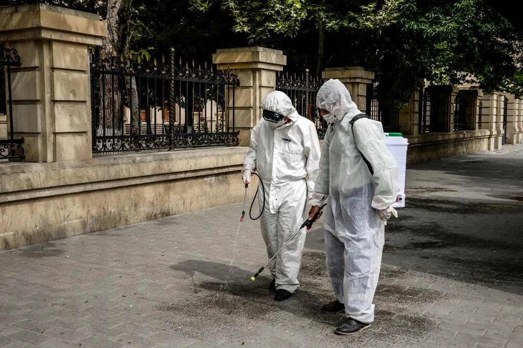 Municipal workers wearing protective suits, amid concerns over the spread of the COVID-19 coronavirus, desinfect a deserted street in Baku. (File/AFP)