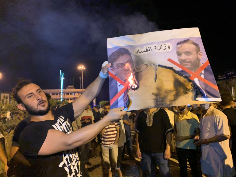 A Libyan protester burns an image of Libyan officials as he protests over announcement of suspension of the Interior Minister Fathi Bashagha during an anti-government protest in Misrata, Libya August 29, 2020. REUTERS/Ayman Al-Sahili
