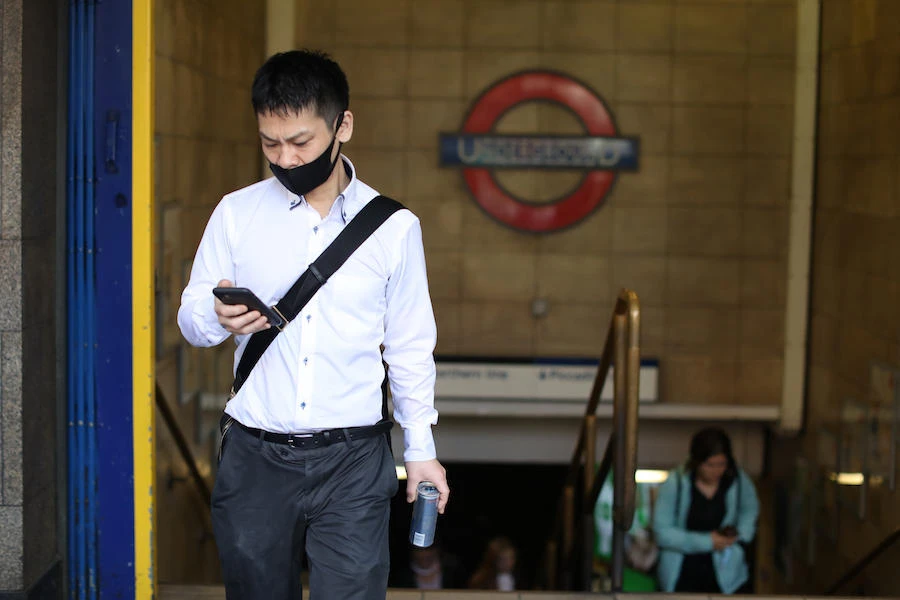 A man wearing a face mask as a precaution against the spread of the novel coronavirus climbs the steps to the street from Leicester Square Underground Station in central London on August 28, 2020. (AFP)