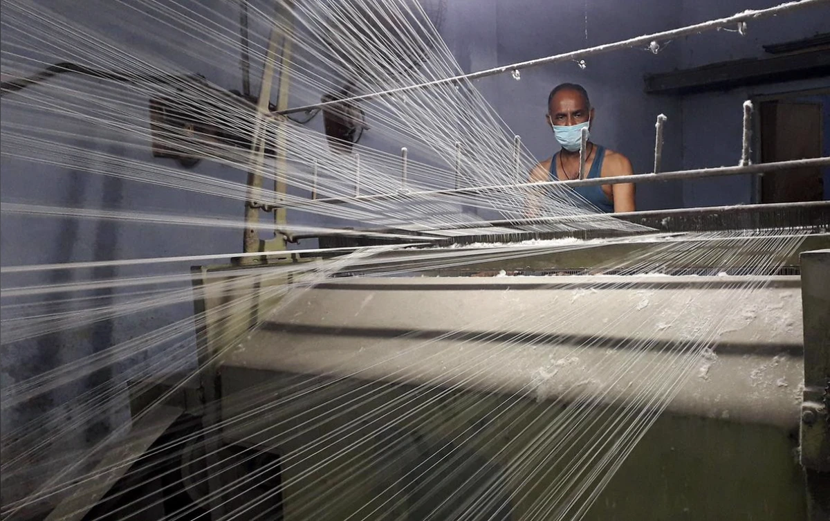 A worker wearing a protective face mask works on a loom in a textile factory, amidst the coronavirus disease (COVID-19) outbreak, in Meerut, July 7, 2020. (Reuters)