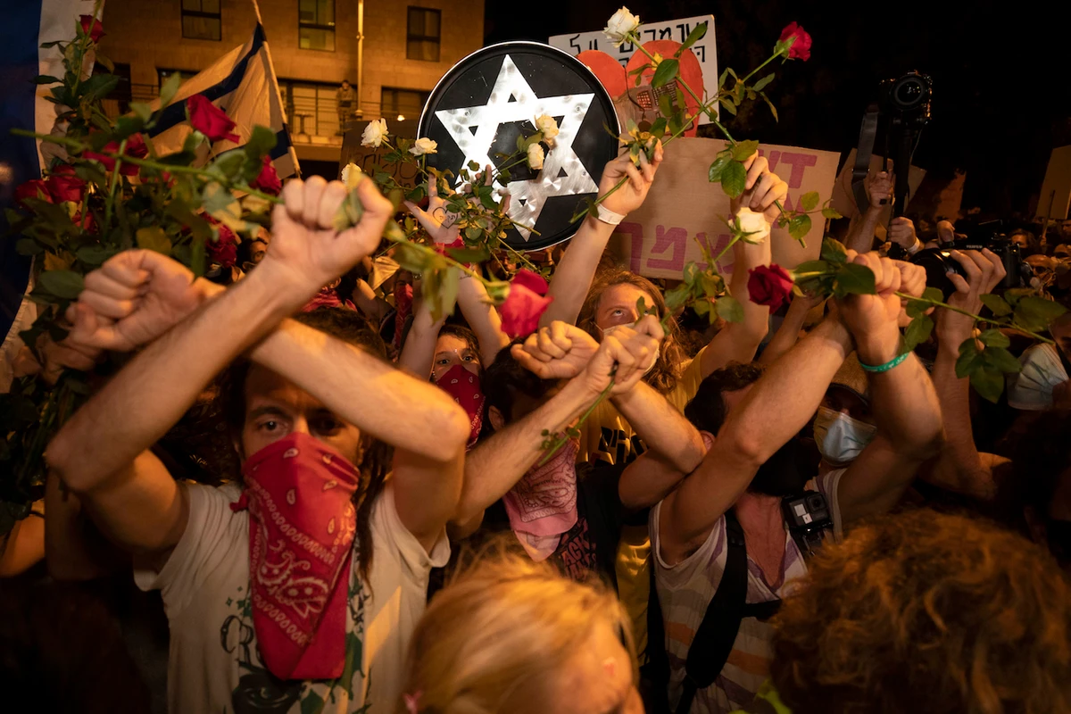Israeli protesters hold flowers and chant slogans during a demonstration against Israeli Prime Minister Benjamin Netanyahu near the Prime Minister's residence in Jerusalem, Saturday, Aug. 15, 2020. (AP)