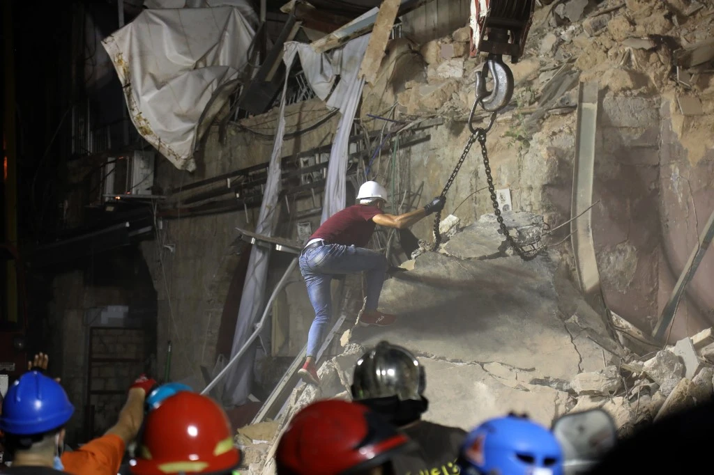 Lebanese and Chilean rescuer workers use a crane to lifts pieces of cement from a badly damaged building in Beirutas in search of possible survivors early on September 4, 2020. (AFP)