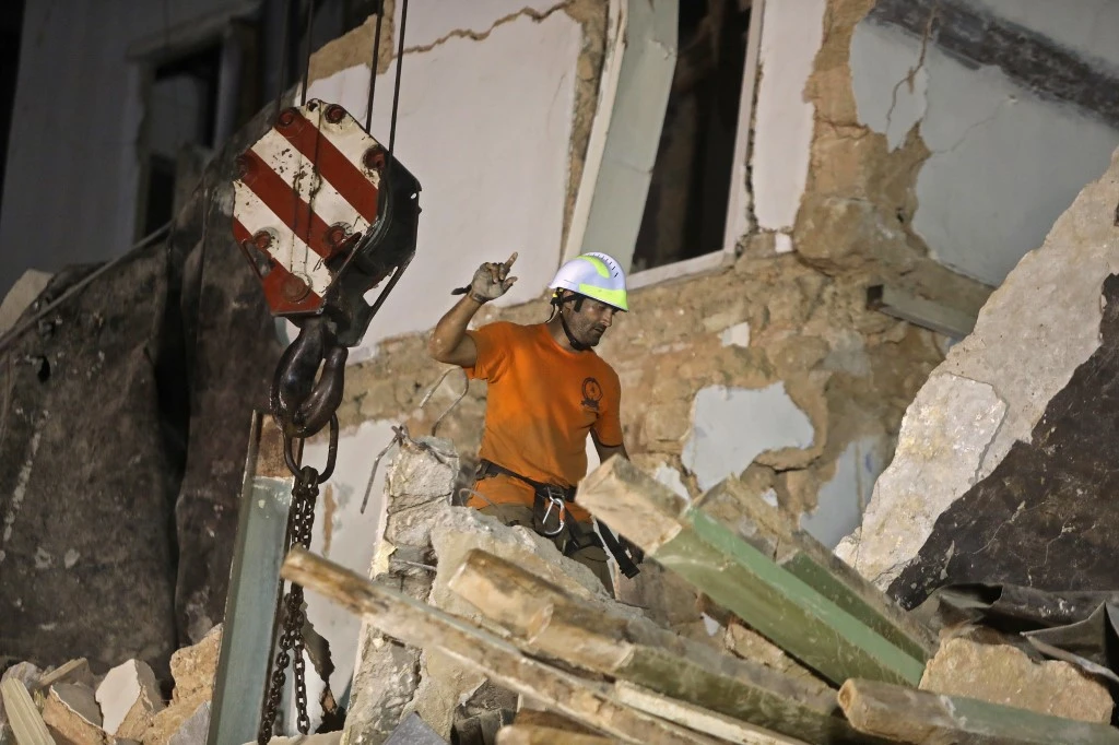 Lebanese and Chilean rescuer workers watch as a crane lifts pieces of cement from a badly damaged building in Beirut in search of possible survivors early on September 4, 2020. (AFP)