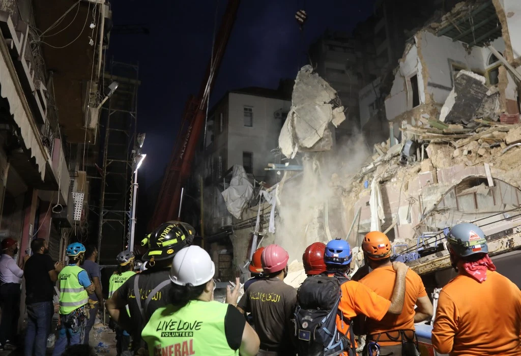 Lebanese and Chilean rescuer workers watch as a crane lifts pieces of cement from a badly damaged building in Beirut in search of possible survivors early on September 4, 2020. (AFP)