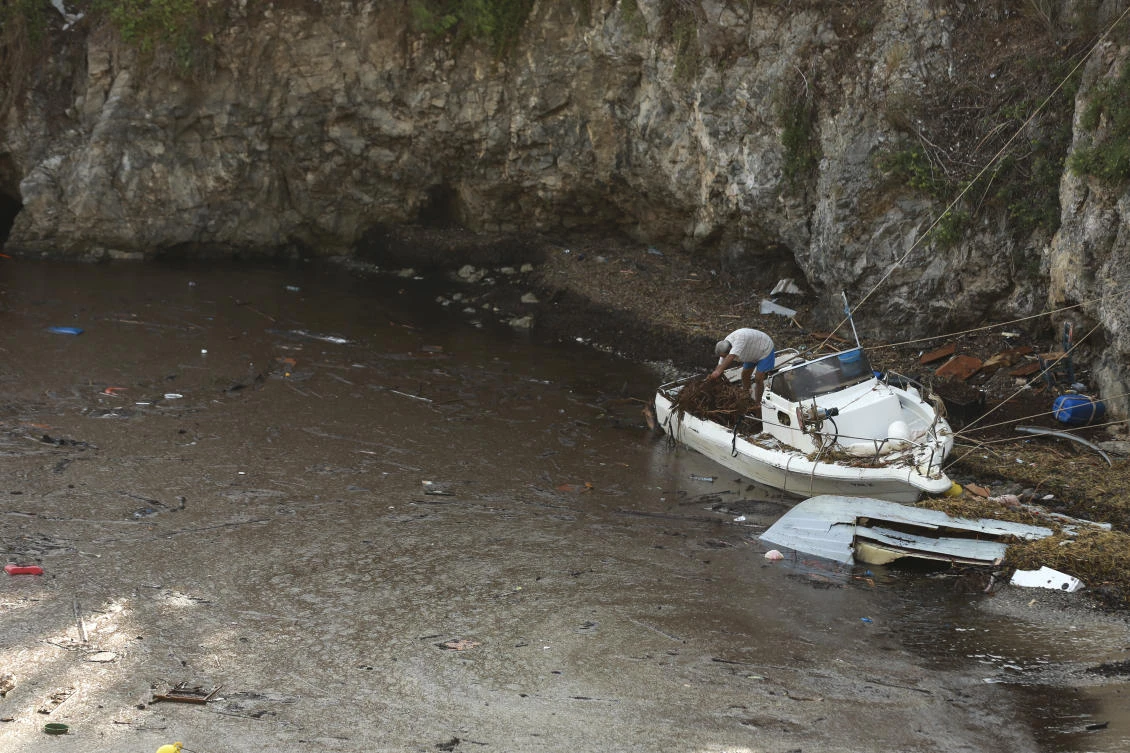 A man cleans his boat from debris following a storm at the village of Assos, on the Ionian island of Kefalonia, western Greece, Sunday, Sept. 20, 2020. A powerful tropical-like storm named Ianos, battered parts of central Greece and some of the western Ionian islands. Emergency workers rescued more than 600 people. (AP Photo/Nikiforos Stamenis)