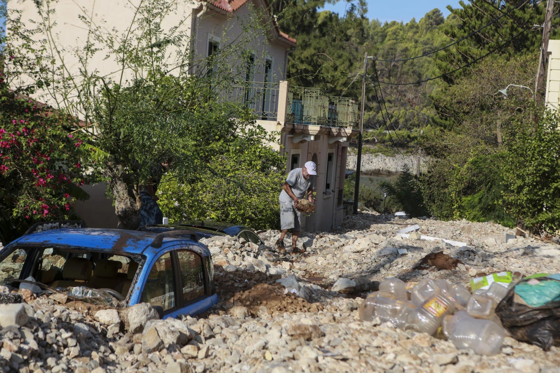 A man carries rocks following a storm at the village of Assos, on the Ionian island of Kefalonia, western Greece, Sunday, Sept. 20, 2020. A powerful tropical-like storm named Ianos, battered parts of central Greece and some of the western Ionian islands, as emergency workers rescued more than 600 people. (AP Photo/Nikiforos Stamenis)