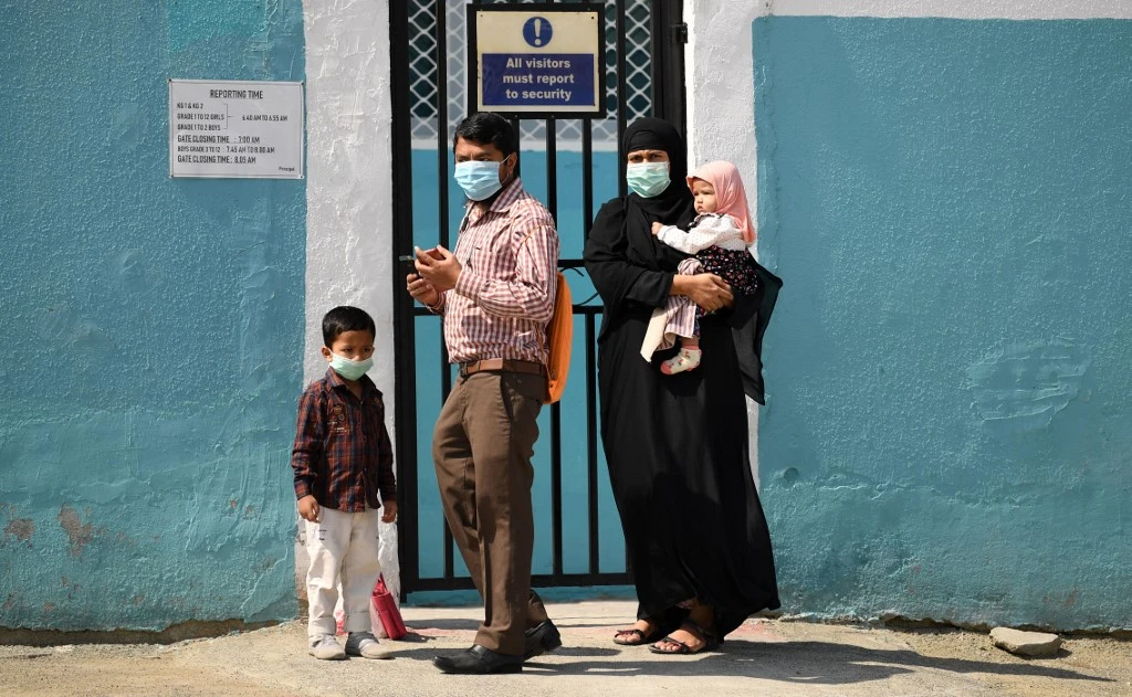 Parents wearing protective masks and their children arrive to a school entrance to register for the new academic year. (File/AFP)