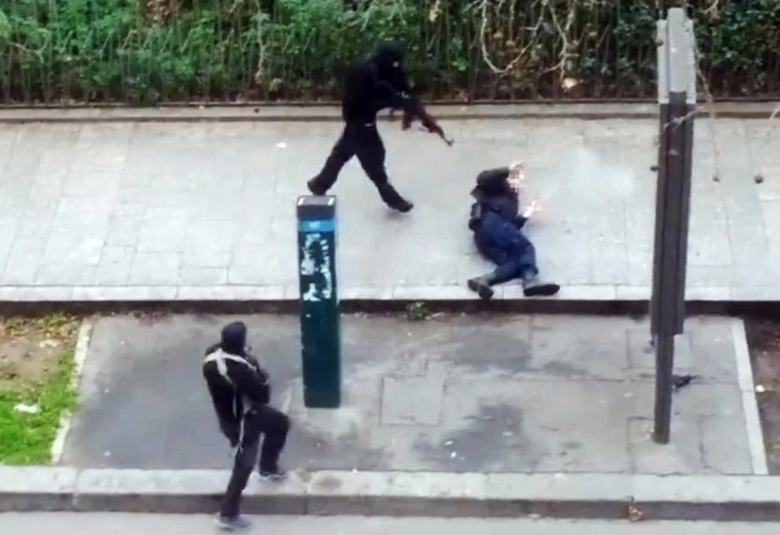 Hooded gunmen Cherif Kouachi and his brother Said Kouachi aiming Kalashnikov rifles toward police officer Ahmed Merabet, before shooting him dead after leaving the office of the satirical weekly newspaper Charlie Hebdo on Jan. 7, 2015. (FILE/AFP/Courtesy of Jordi Mir)