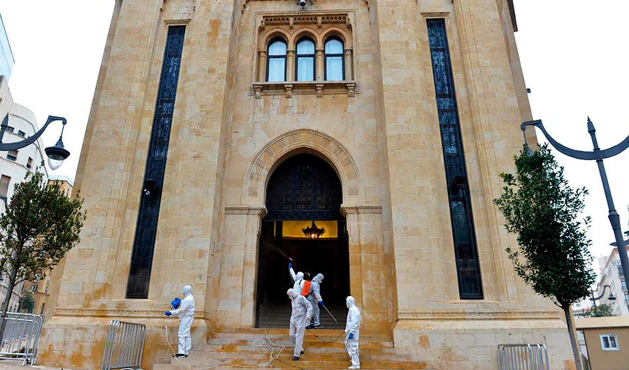 In this photo released by the Lebanese Parliament media office, workers wearing protective gear spray disinfectant as a precaution against the new coronavirus outbreak, at the entrance of the Lebanese Parliament, in Beirut, Lebanon, Tuesday, March 10, 2020. (AP)