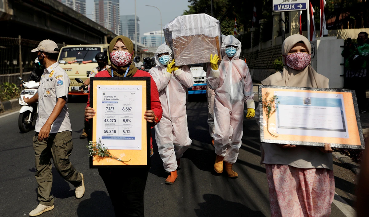 Government workers wearing protective suits carry a mock-up of a coffin of a coronavirus disease (COVID-19) victim as others carry signs displaying information about the number of COVID-19 cases on a main road to warn people about the dangers of the disease as the outbreak continues in Jakarta, Indonesia, August 28, 2020. (Reuters)