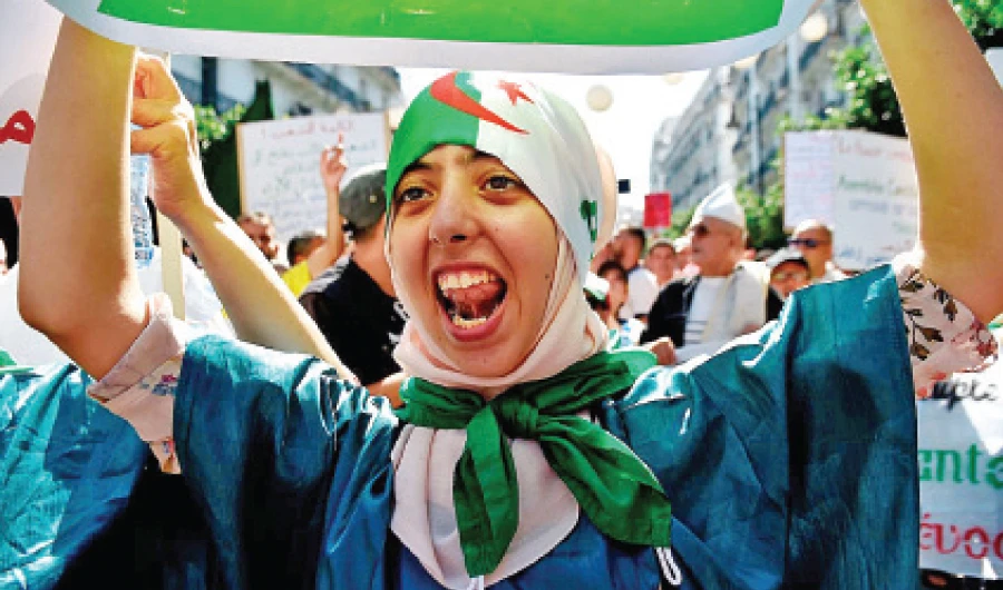 An Algerian woman wearing the national flag as a headscarf chants during an anti-government demonstration led by Hirak, or ‘Movement,’ in Algiers. (AFP/File)