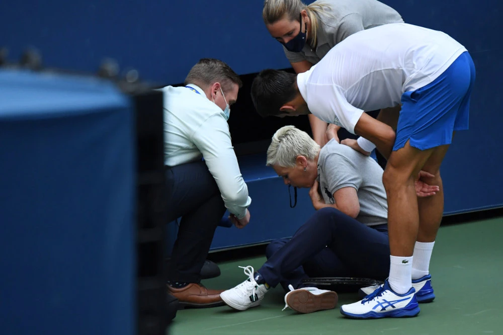 Novak Djokovic and a tournament official tend to a linesperson who was struck with a ball by Djokovic against Pablo Carreno Busta of Spain on day seven of the 2020 US Open tennis tournament at USTA Billie Jean King National Tennis Center in Flushing Meadows, New York. (Danielle Parhizkaran-USA TODAY Sports)