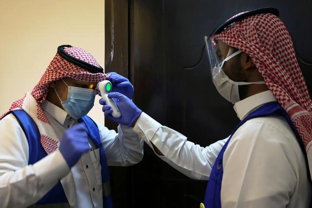 A Saudi volunteer supervisor checks the temperature of another volunteer before preparing boxes of Iftar meals provided by a charity organization during the holy month of Ramadan, during a coronavirus outbreak in Riyadh, Saudi Arabia, May 10, 2020. (Reuters)
