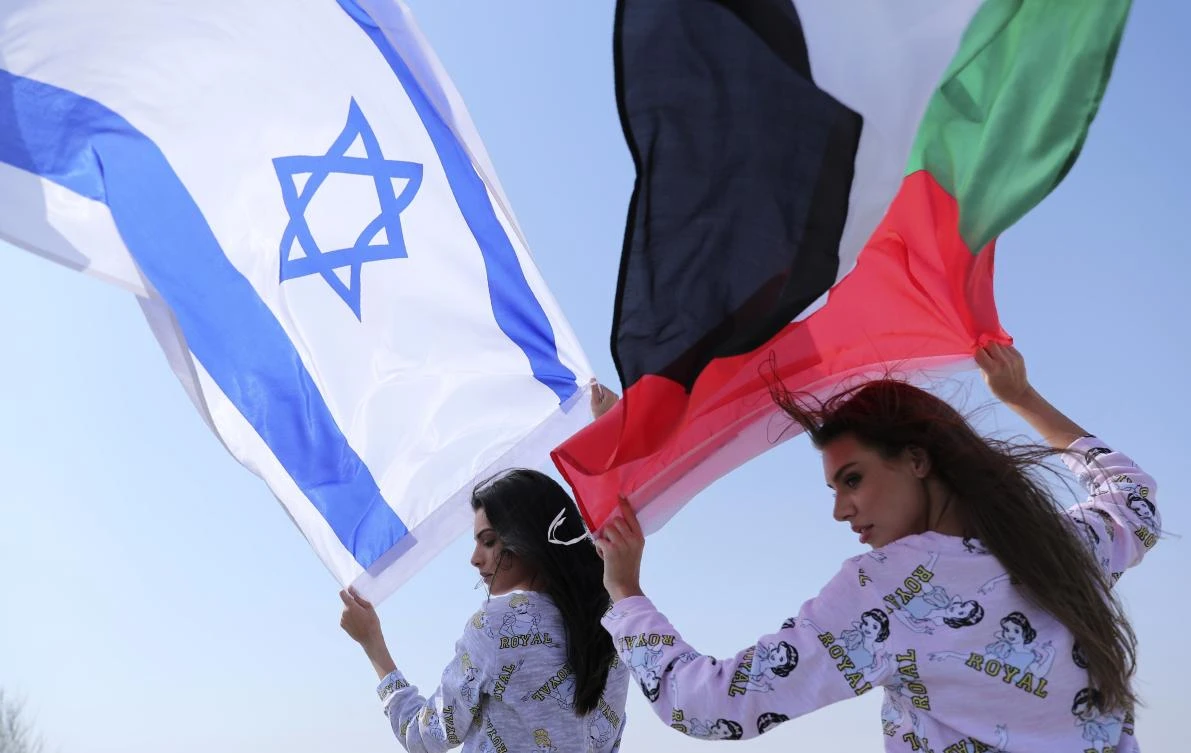 Israeli model May Tager, left, holds Israel’s flag while next to her Anastasia Bandarenka, a Dubai-based model originally from Russia, waves the Emirati flag, during a photo shoot in Dubai. (AP)