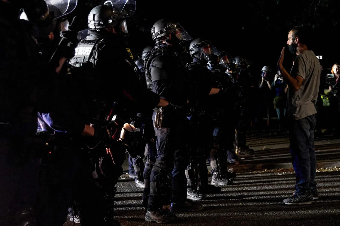 A protester faces Oregon police wearing anti-riot gear during the 100th day and night of protests against racism and police brutality in Portland, Oregon, on September 5, 2020. (AFP)