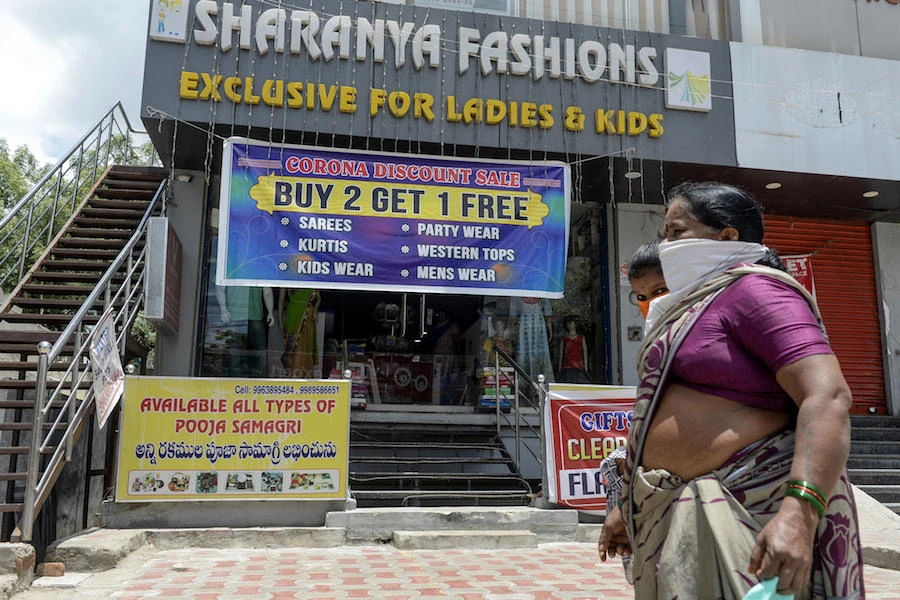 Residents walk past a readymade garment shop displaying a banner reading 'Corona Discount Sale' offer as the country has recorded more than one million COVID-19 coronavirus cases, in Hyderabad on July 18, 2020. (File/AFP)