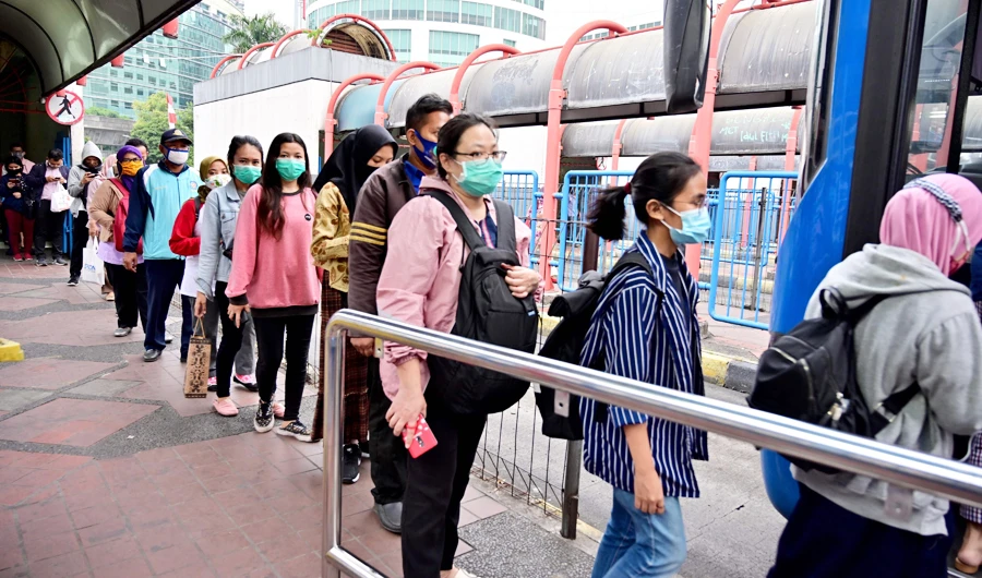 Indonesian people queue to get on a bus at the Blok M terminal in Jakarta on September 10, 2020. (AFP)