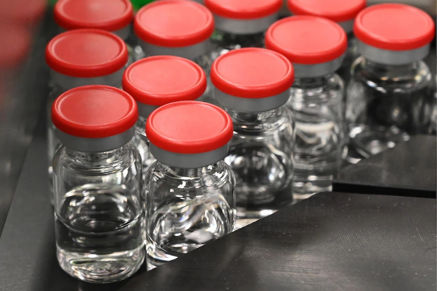 Capped vials are being pictured during filling and packaging tests for the large-scale production and supply of the University of Oxford’s COVID-19 vaccine candidate, AZD1222, conducted on a high-performance aseptic vial filling line on September 11, 2020. (AFP)