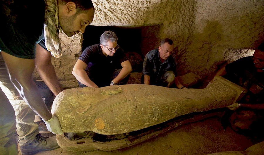 handout picture released by the Egyptian Ministry of Antiquities on September 6, 2020, shows Secretary General of the Supreme Council of Antiquities Mostafa Waziri (C) inspectiong one of thirteen 2500 year-old wooden coffins discovered in a burial shaft at the desert necropolis of Saqqara south of the capital. (AFP)