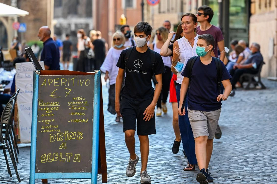 Teenagers wearing a face mask stroll past a restaurant across Rome's Jewish Quarter on September 15, 2020 during the COVID-19 infection, caused by the novel coronavirus. (AFP)